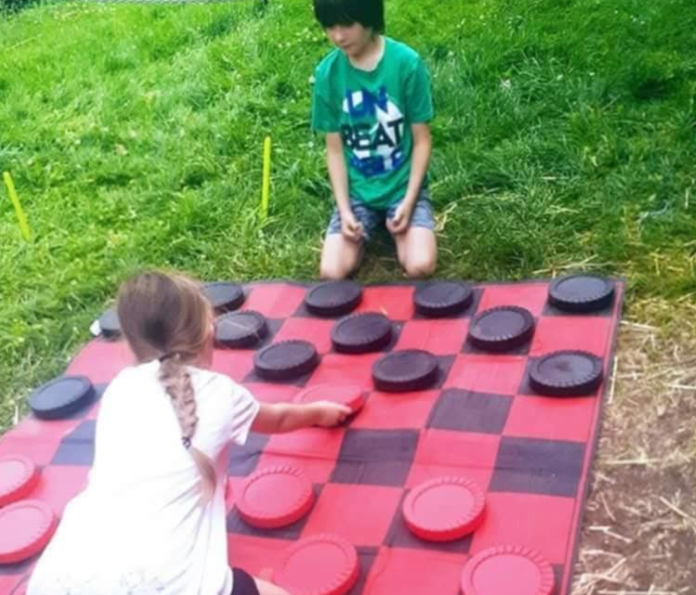 Two children playing on a large chequers game board